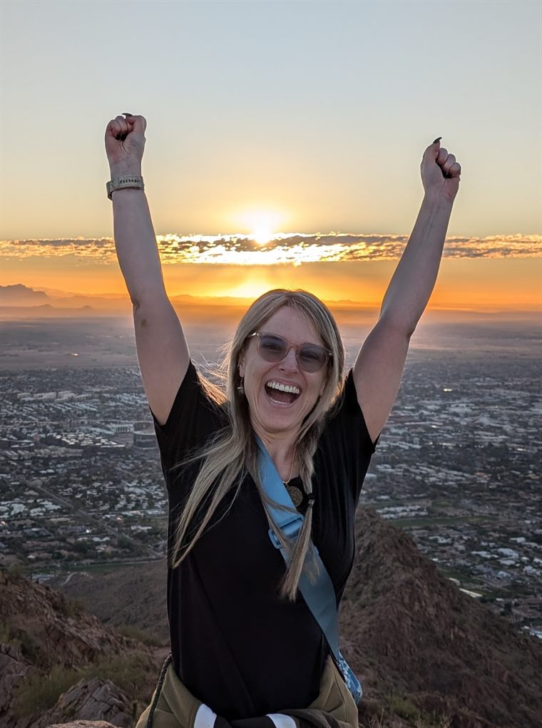 Masha Thomas at the summit at sunrise with arms raised